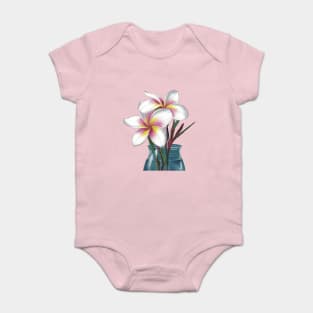 Small Bouquet of Plumeria Flowers with White Petals and Yellow and Pink Accents, Placed in a Blue Vase Against a Plain Baby Bodysuit